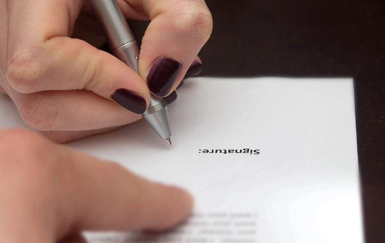 A person writing on top of a piece of paper.