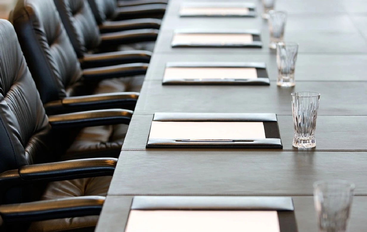 A long table with many chairs and place mats.