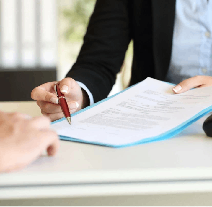 A person is signing papers on top of a table.